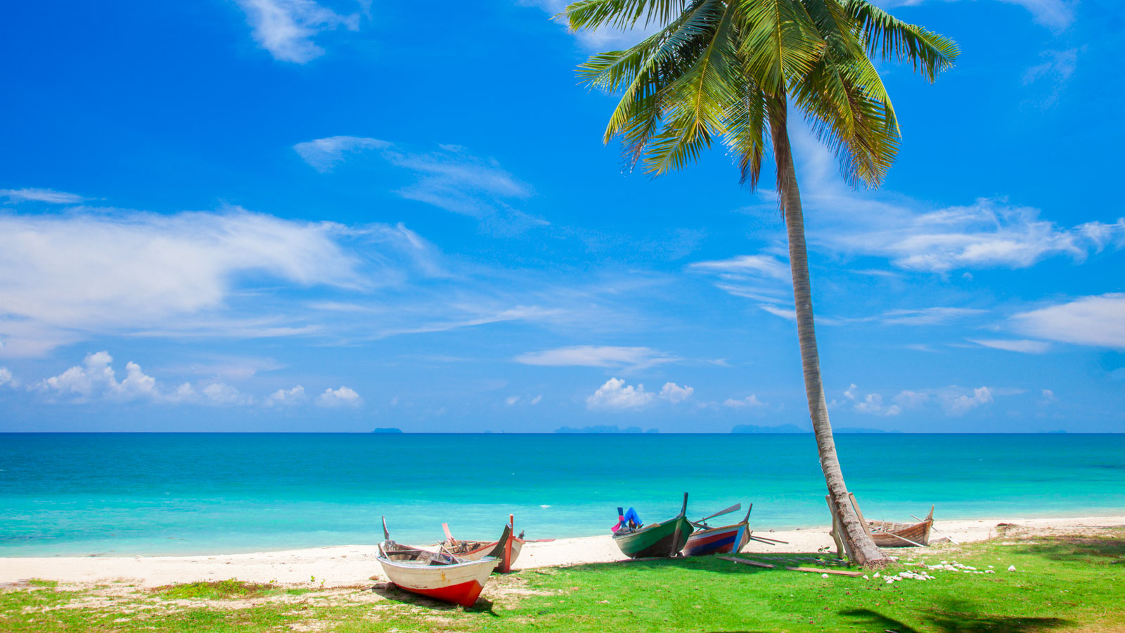 Boats on beach in Thailand with clear blue water