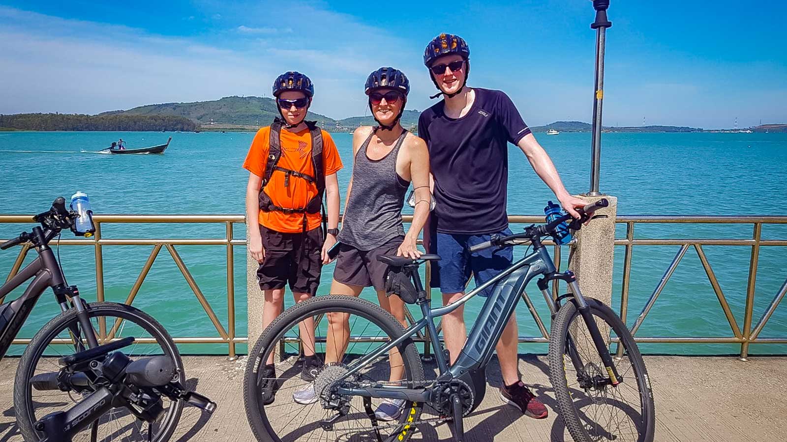 Three cyclists posing in front of ocean in Thailand