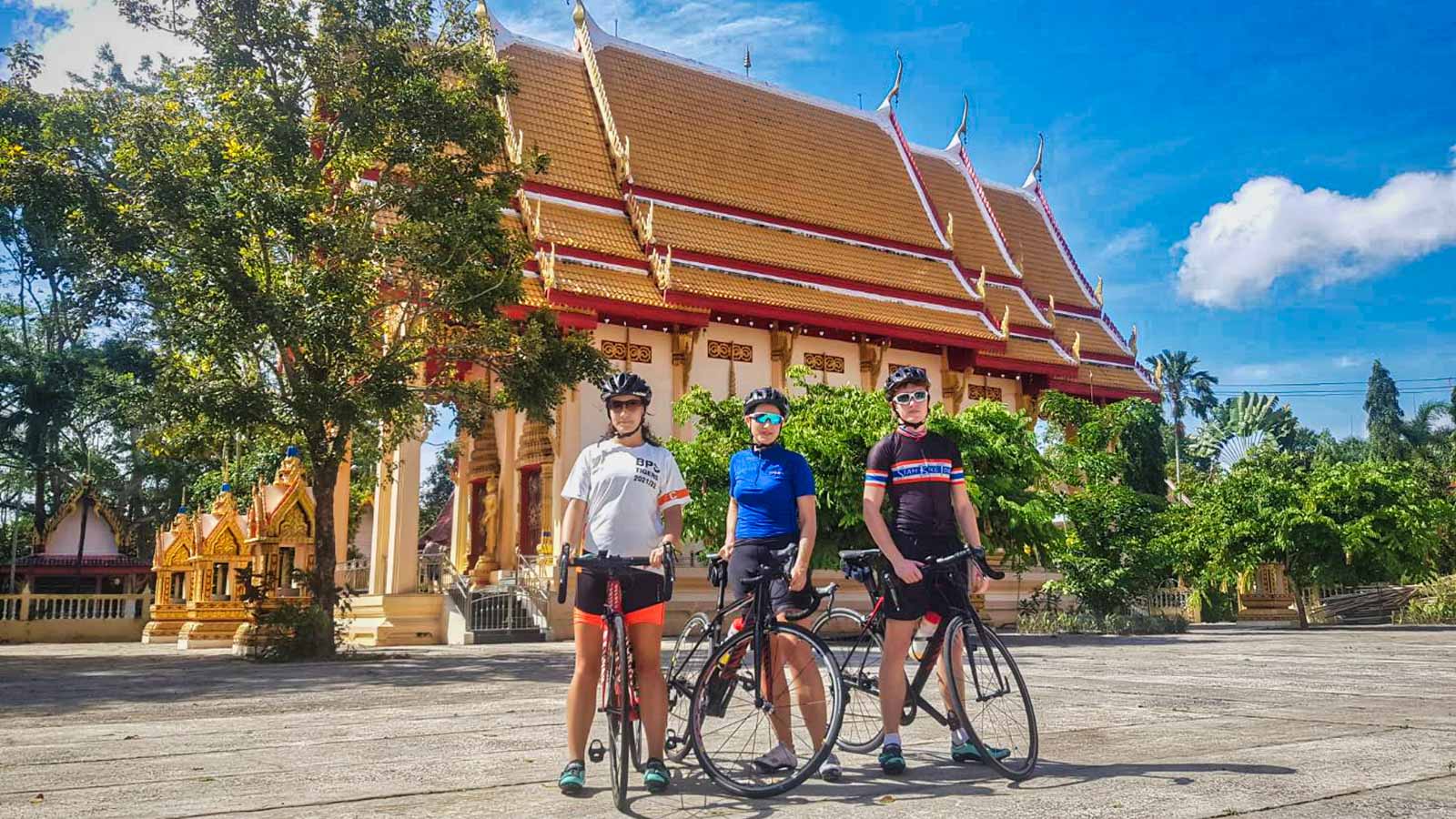 Cyclists posing in front of Thai temple
