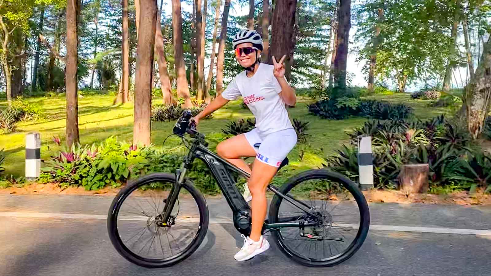 Thai cyclist riding e-bike through Sririnat National Park and waving to camera